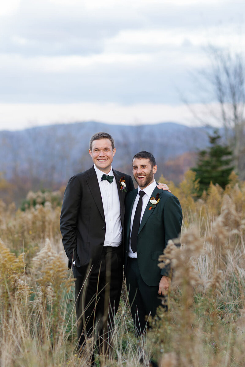 Two grooms smile for portrait in North Carolina fields