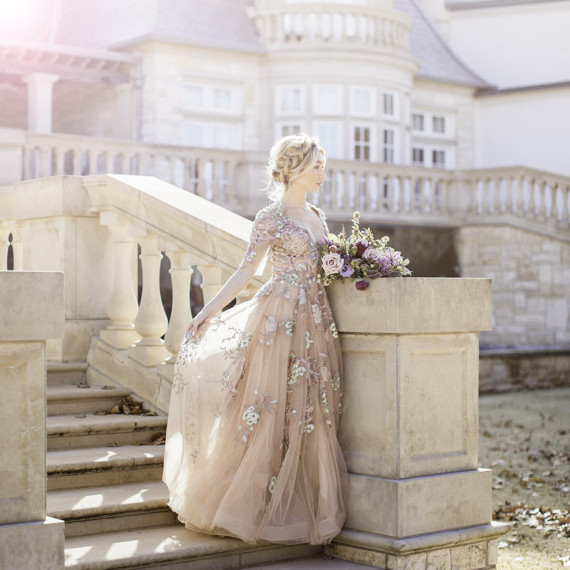 Blond bride standing on staircase with flower bouquet