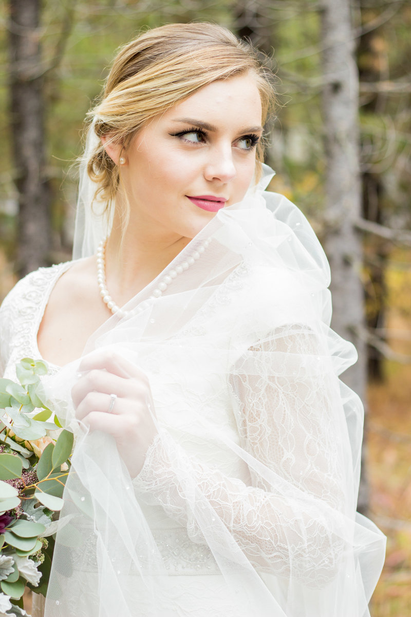 Affordable Washington elopement photographer captures bride holding veil during forest wedding