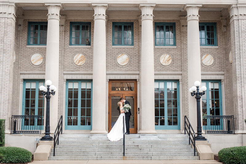 Bride and groom kiss in front of Historic Post Office