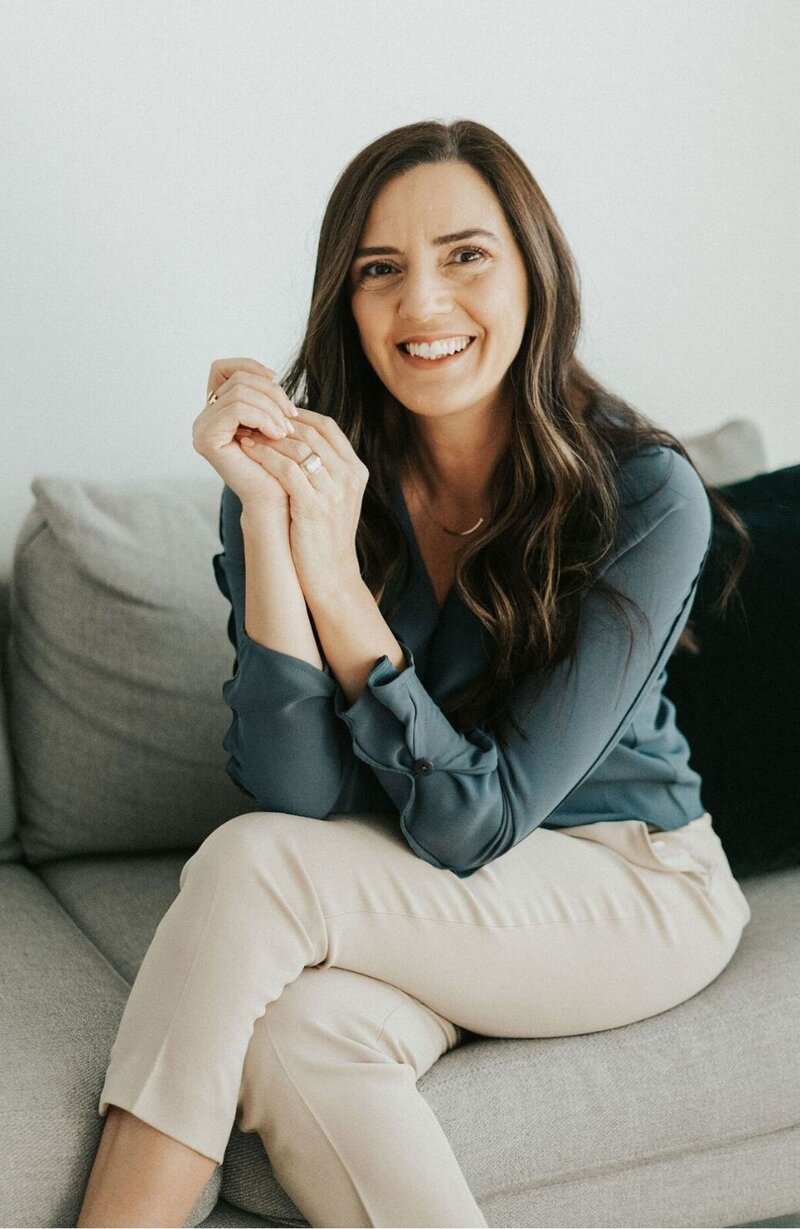Idit Sharoni sits on a sofa as she smiles at the camera. She offers couples therapy and marriage counseling in FL, online couples counseling, and other services. Learn more about communication therapy for couples in Florida today!