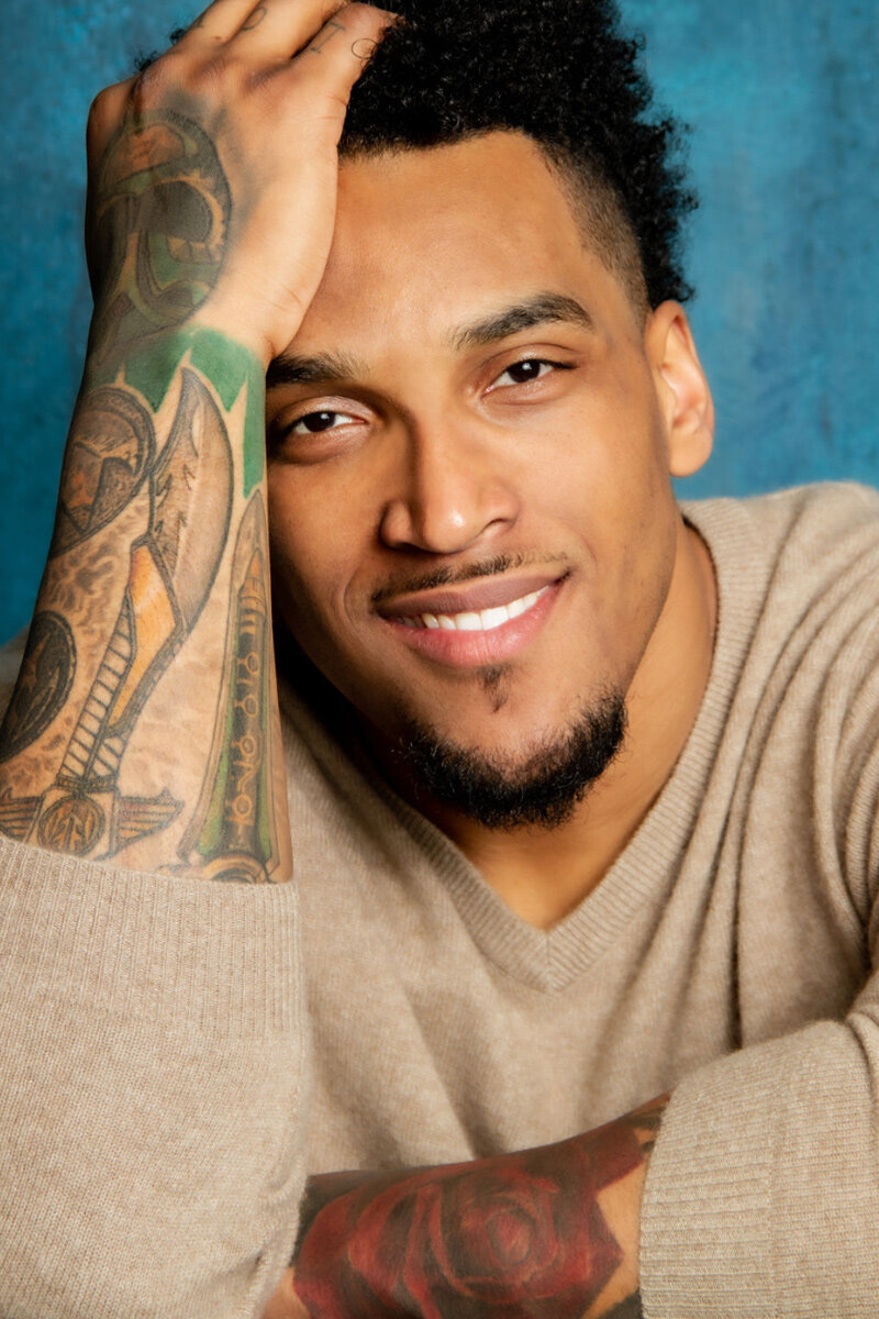Personal Branding Headshot Joe Barksdale against blue background hand to his forehead while smiling