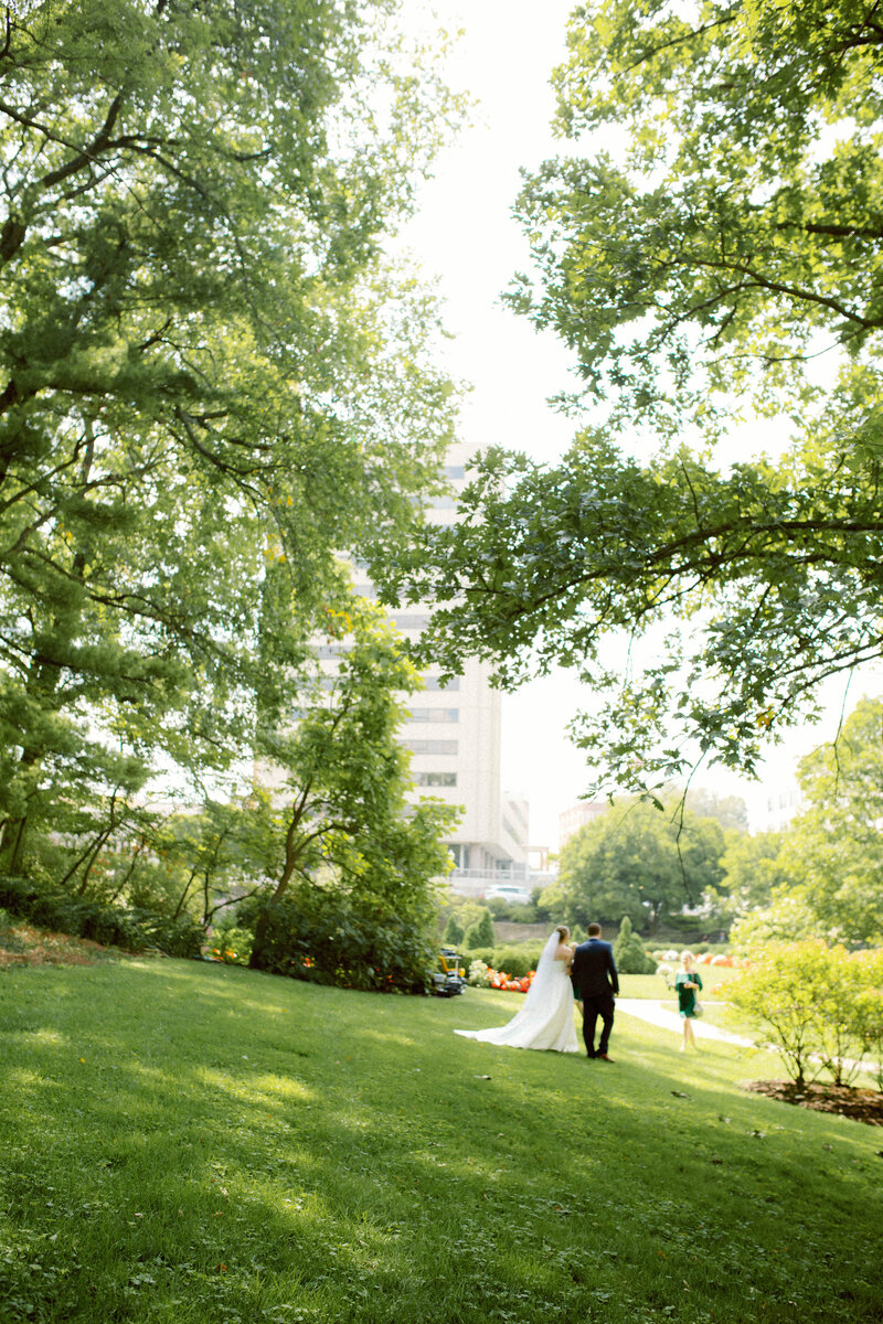 Bride and groom walking toward their ceremony surrounded by trees, captured in a calm, authentic, and emotional documentary style that emphasizes presence and connection