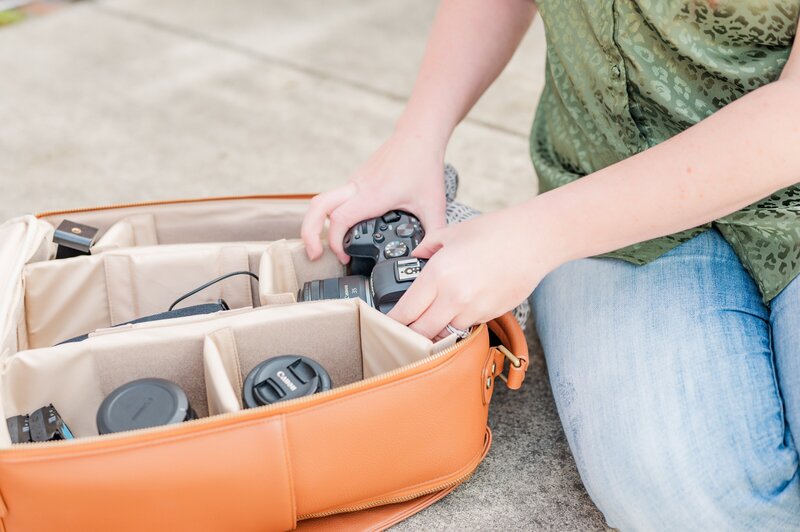 woman putting lenses into her camera bag