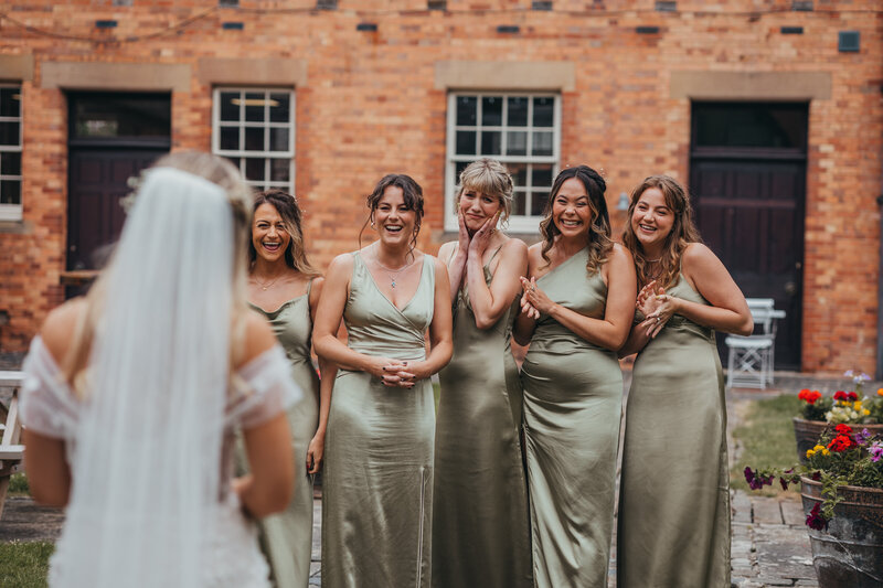 bridemaids reacting with excitement to bride in dress