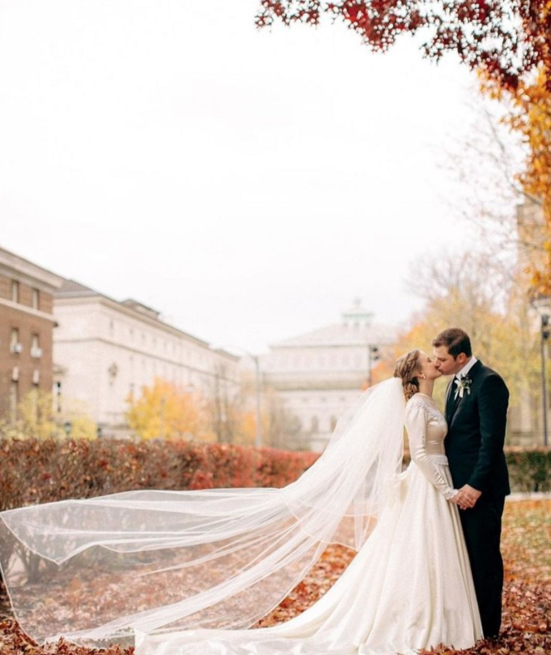 Fall bride and groom portrait with veil flying in the wind
