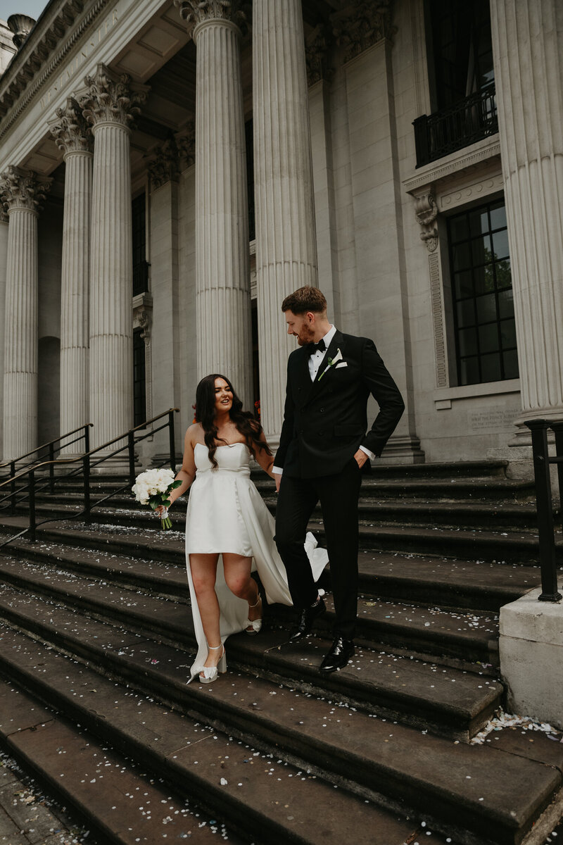 Bride and groom walk down the steps after their ceremony at The Old Marylebone Town Hall. 