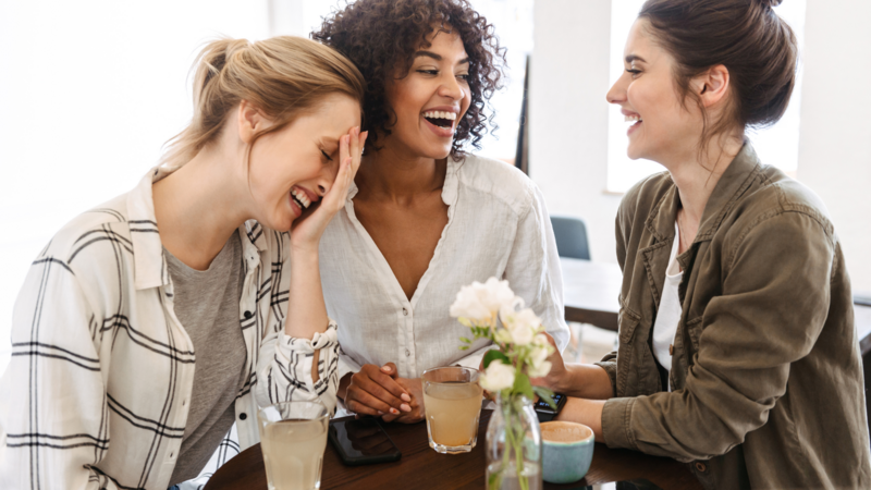 Three woman standing and laughing with each other