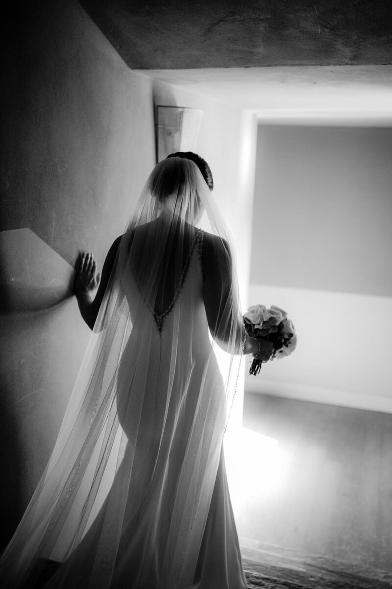 Bride walking towards the ceremony going down the stairs, in black and white