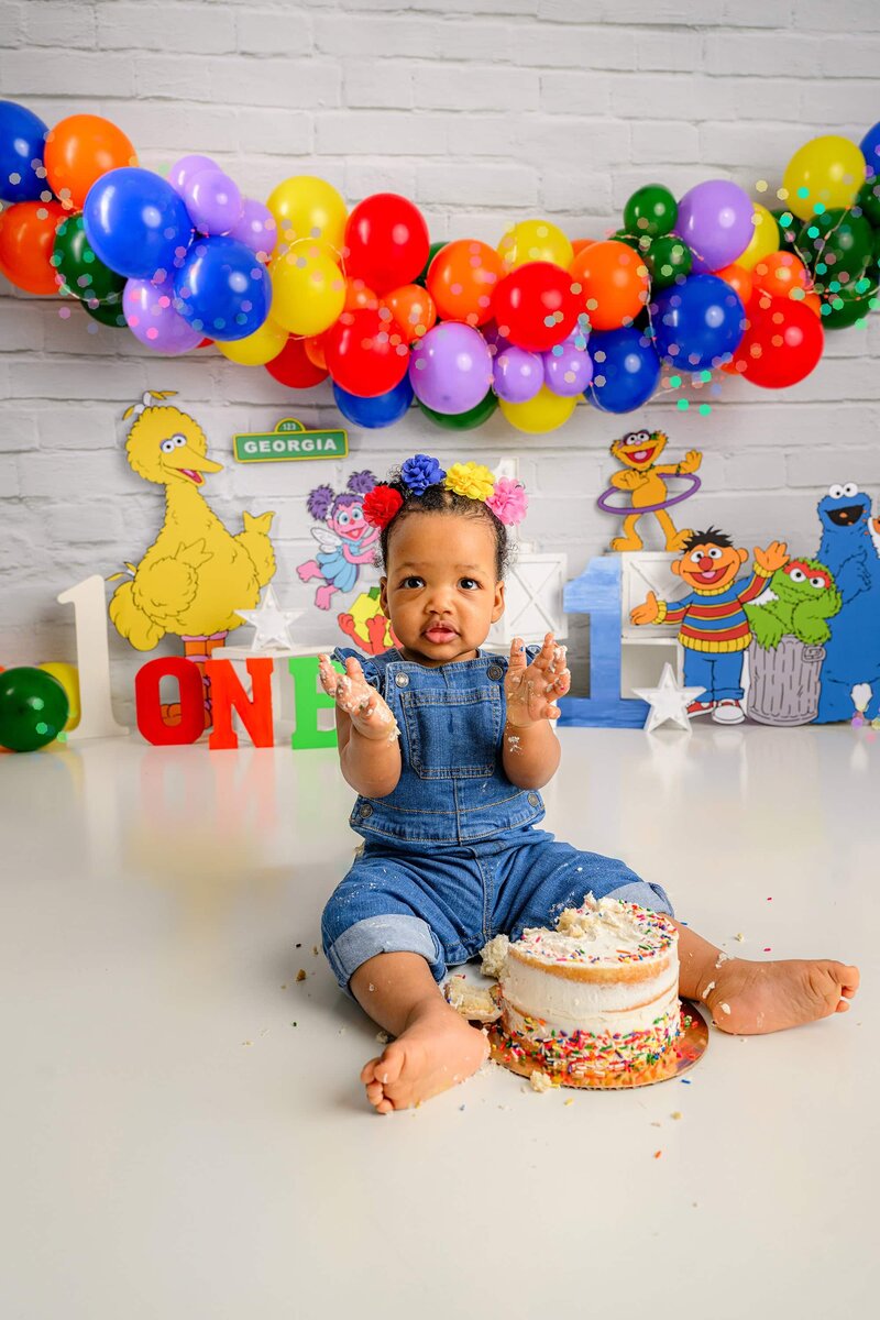 litte girl clapps as she has fun in her studio cake smash