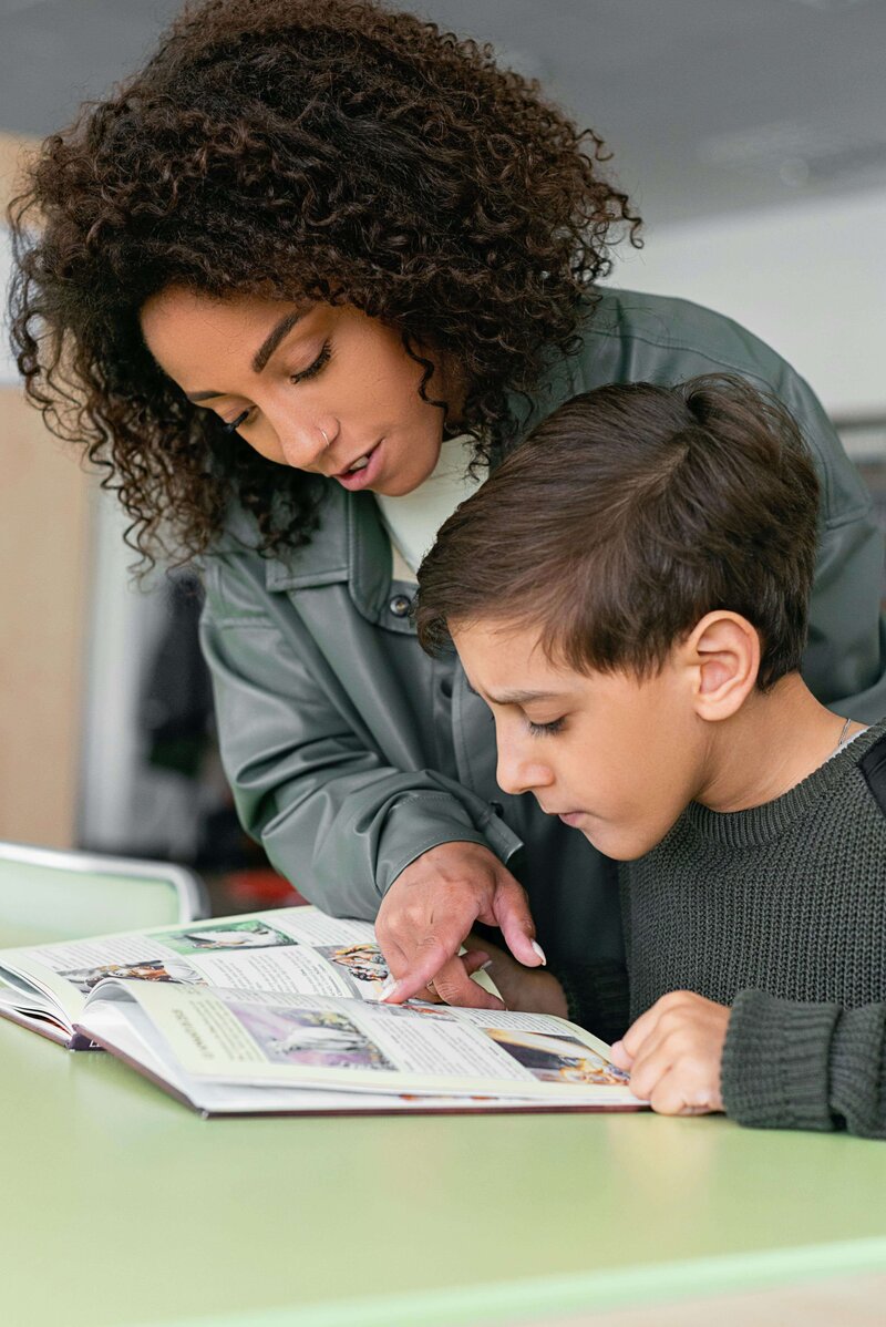 A young male student being helped by a teacher in school
