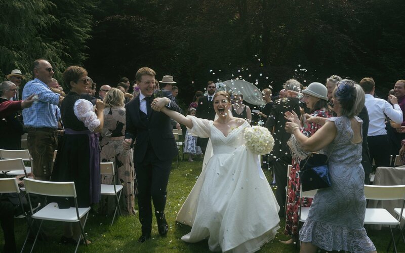 Joyful newlyweds celebrating their marriage by walking through a shower of colorful confetti, embracing their love and happiness on their special day