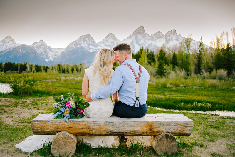 Jackson Hole wedding photographers capture Grand Teton wedding with bride and groom sitting on bench together