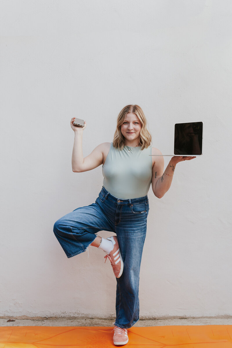 Lifestyle brand photo of Talia Falcon Blackburn, social media manager & owner of Om Media Marketing, balancing laptop & phone while in yoga pose Greensboro NC