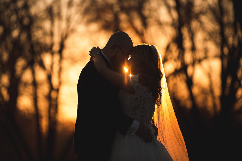 The sun is lighting a bride's vail in a wedding portrait captured during the golden hour.