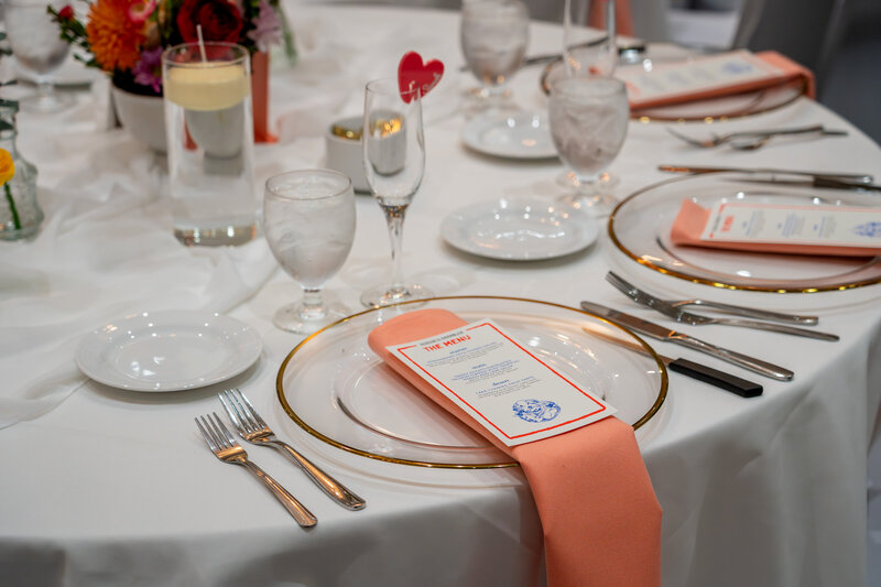 Elegant wedding table setting with peach napkins, gold-rimmed plates, and floral accents, photographed by wedding photographer Niko Coric - Lumen Clarity Media