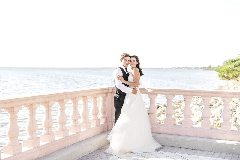 bride and groom embracing by the ocean