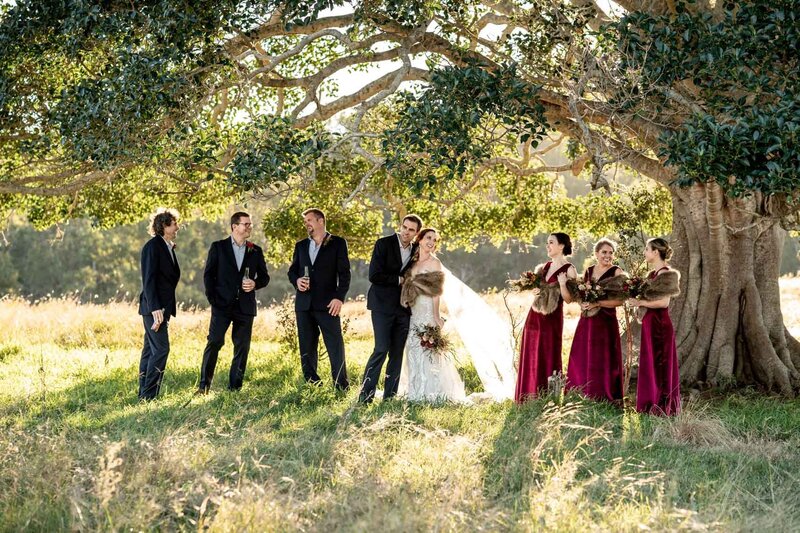 Sweet bride and groom with bridesmaids and groomsmen under the tree