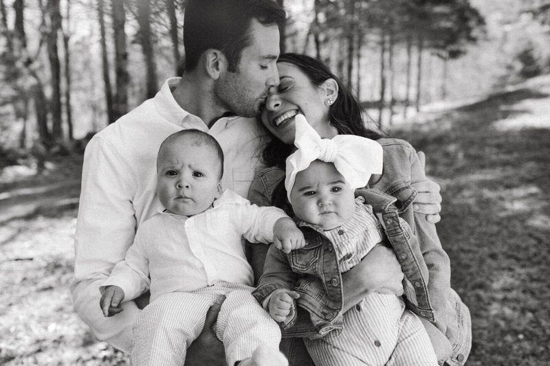 Father kissing mother while holding boy and girl twins
