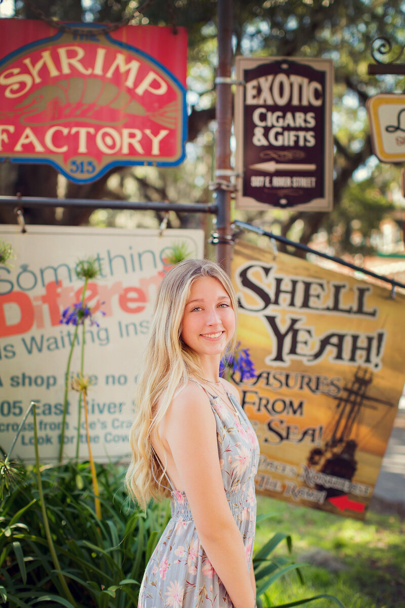 Ava in Savannah for her senior pictures with local signs behind her.