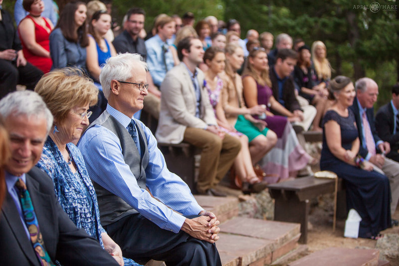 Wedding guests sitting outside at an amphitheater at a summer camp wedding at Colorado Mountain Ranch in Boulder