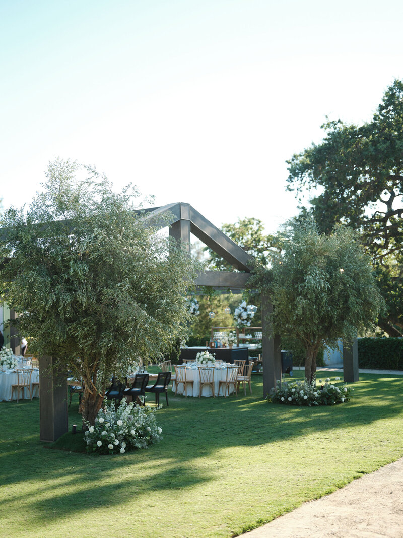 Wedding reception tables set up in an outdoor arched corridor overgrown with ivy