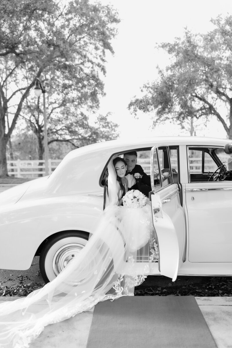 A wedding couple sitting in a vintage car in a black and white photo by Florida wedding photographer Angelika Krug Photo & Film.