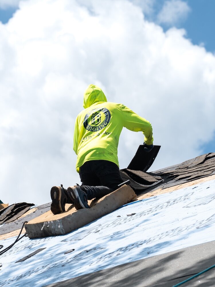 A roofer is tearing off shingles of a Kansas City home that needs a new roof