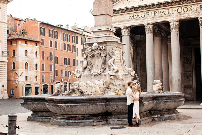 Wide angle shot of a couple standing in front of the fountain at the Pantheon. Taken by Rome Photographer, Tricia Anne Photography