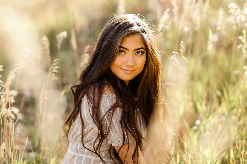 Sunkissed sunset senior picture of a girl in a field of tall grass