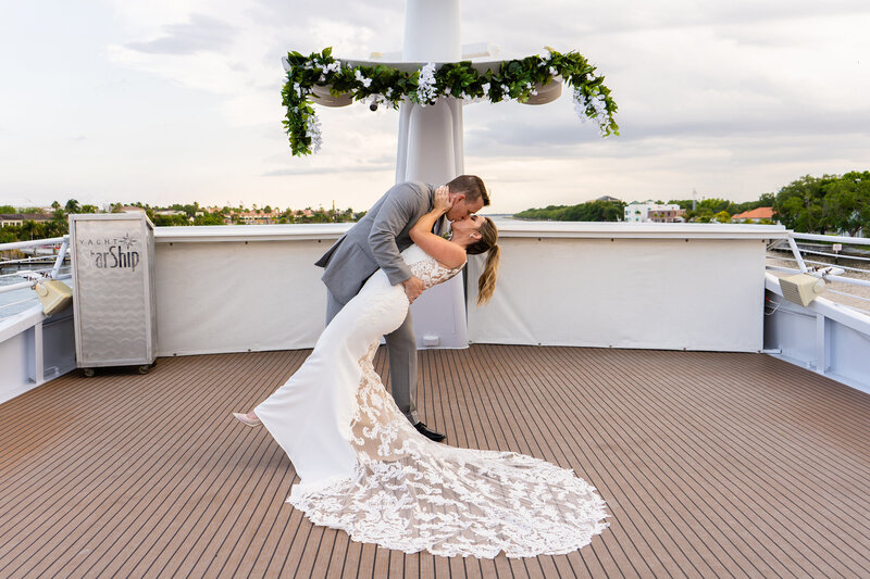Bride and groom sharing a dramatic dip-and-kiss on the deck of a yacht during their destination wedding, captured in a bright, adventurous style perfect for Colorado couples who love travel and water-inspired celebrations.