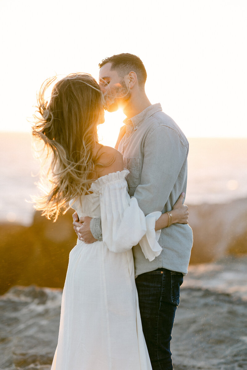 Engaged couple kiss at sunset during engagement photography session