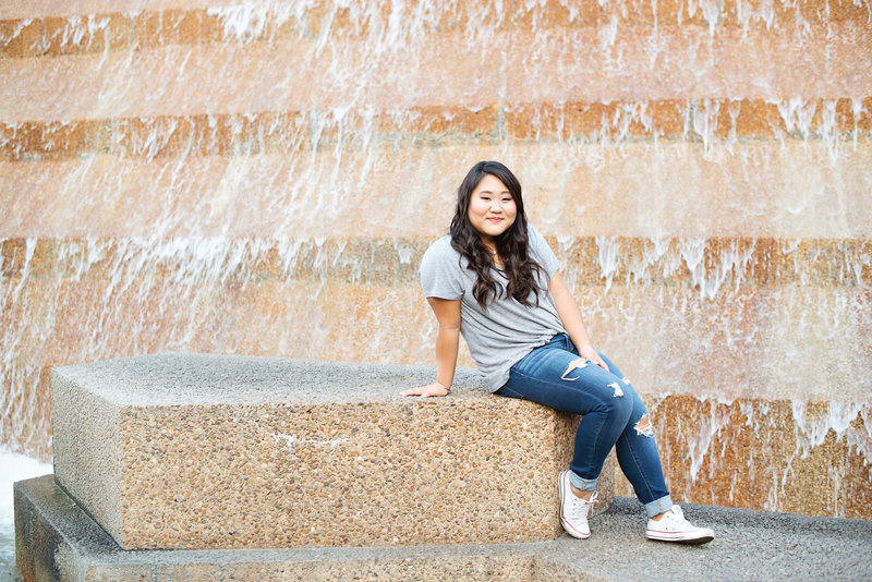 High School Senior sitting in the fountain at the Fort Worth Water Garden wearing jeans and Chuck Taylors.