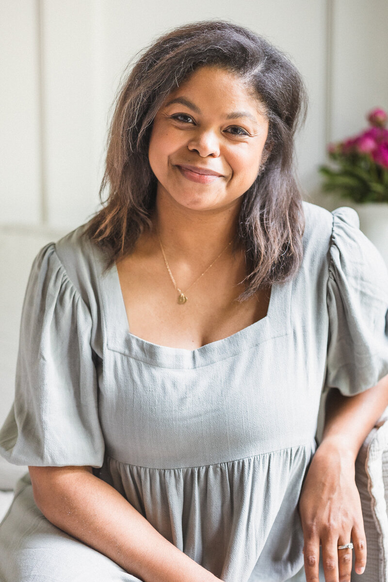 headshot of black woman in family living space wearing grey dress
