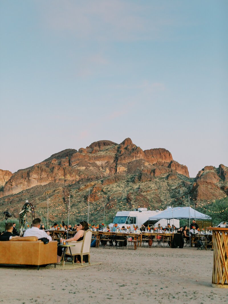 people relaxing at a wedding by a rocky mountain in the desert