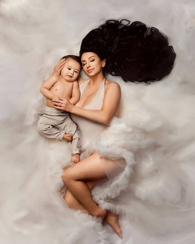 Beautiful portrait of a mom laying down in fluffy white gown embracing her son in my Arizona Family studio