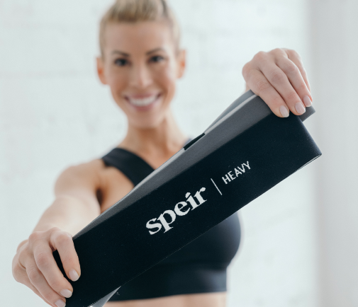 Co-founder, Andrea Speir, holding Speir Pilates branded resistance bands and showing them to the camera