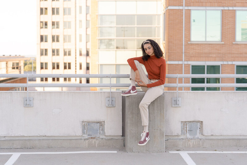 girls sitting on the railing of a parking garage during senior photography in Reston, VA