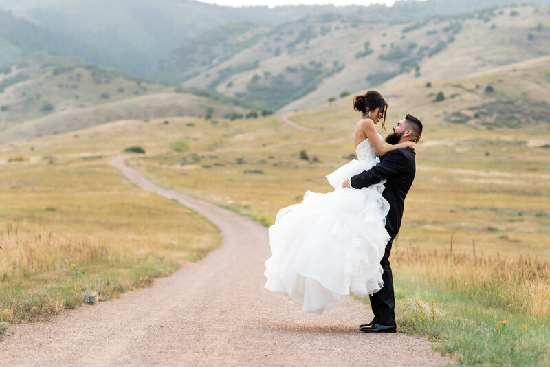 Elopement Photographer, a groom holding bride up in his arms on a trail in the hills