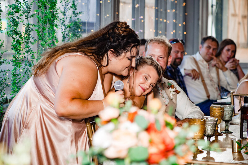Maid of honor hugging bride after giving her wedding toast