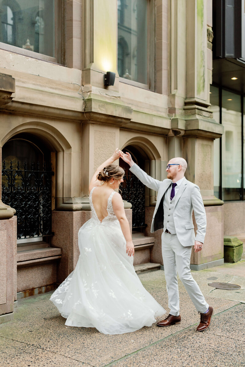 Groom lifting arm up so bride can twirl around at Halifax wedding, Nova Scotia