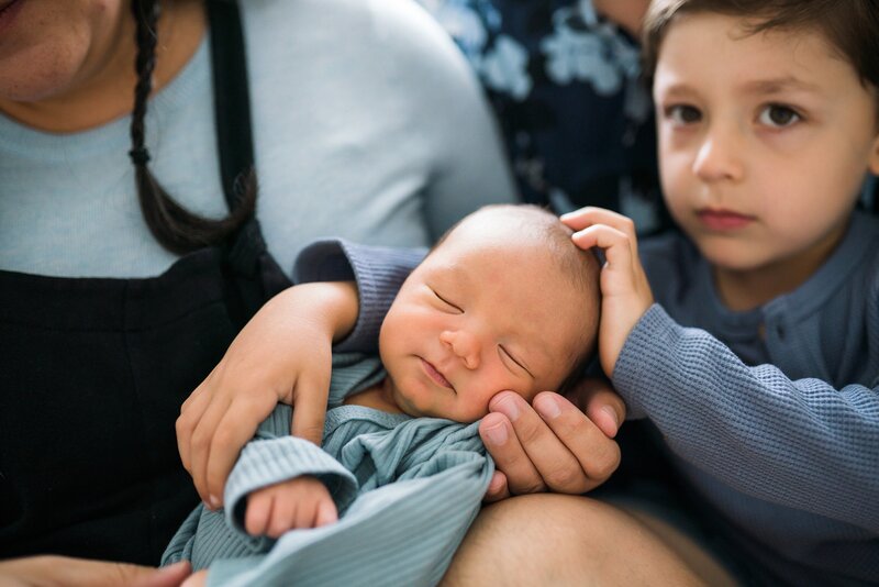 Newborn baby cuddled by older brother during Seattle lifestyle newborn portraits