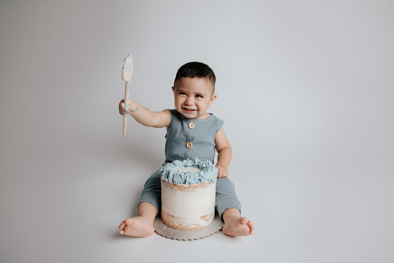 cute one year old boy eating a cake during his cake smash session in  a Tucson studio