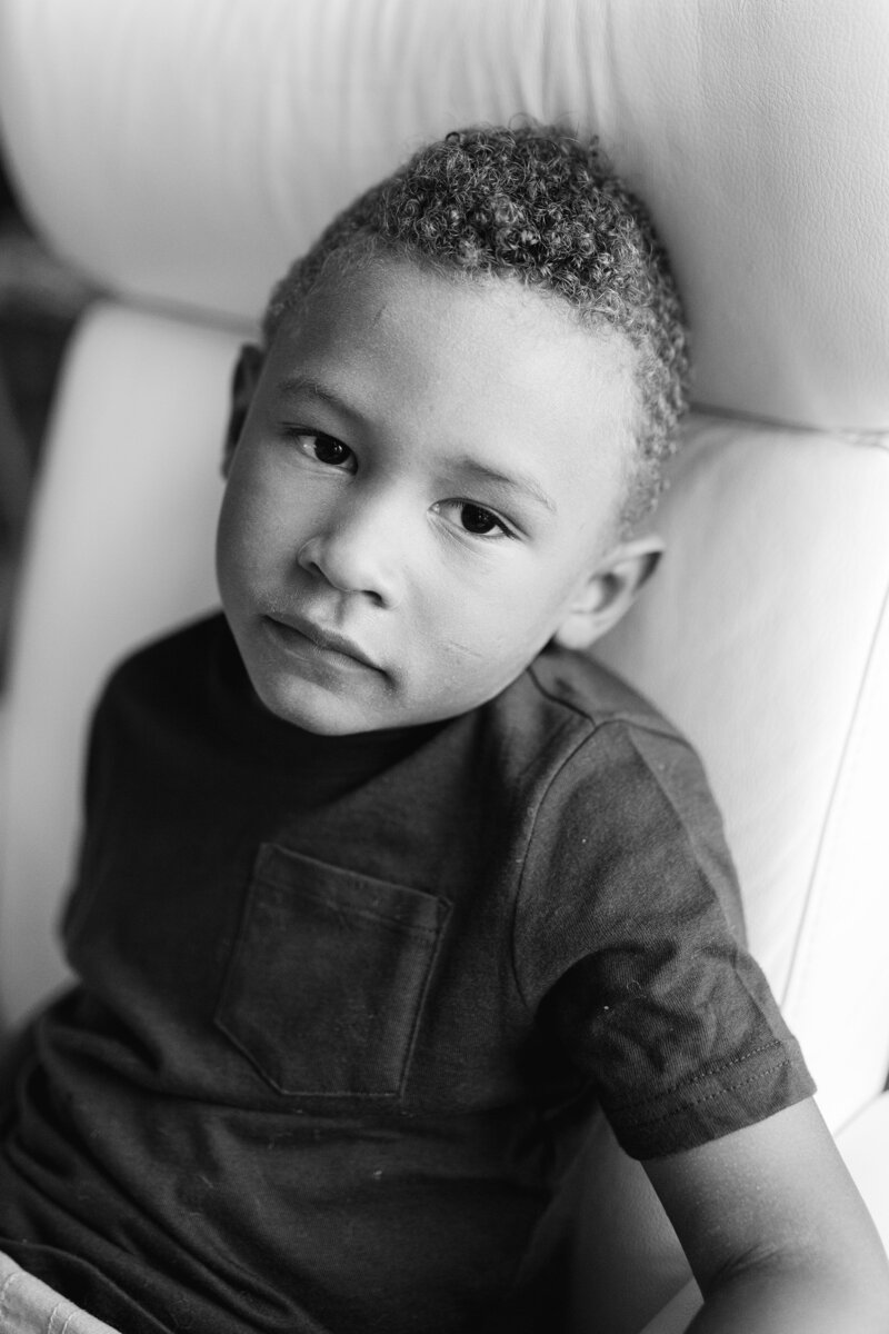 A black and white image of a little boy looking serious during his family photo session with Priscilla Baierlein Photography.