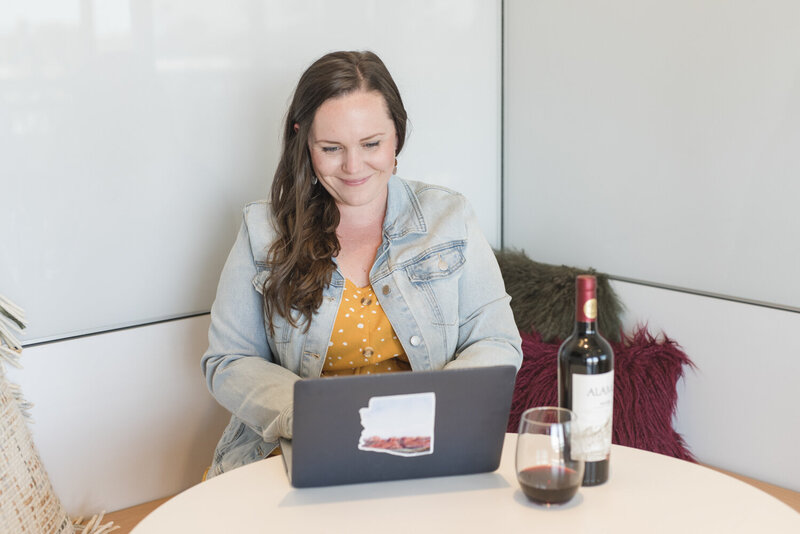 woman working at a laptop with a glass of wine