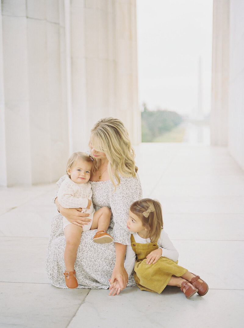 A mother sits in the Lincoln Memorial with her two daughters