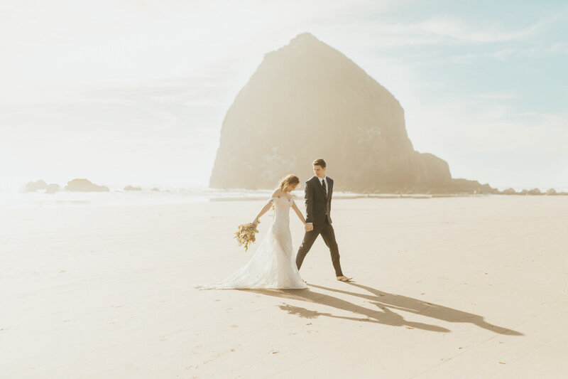 bride and groom holding hands walking on the coast