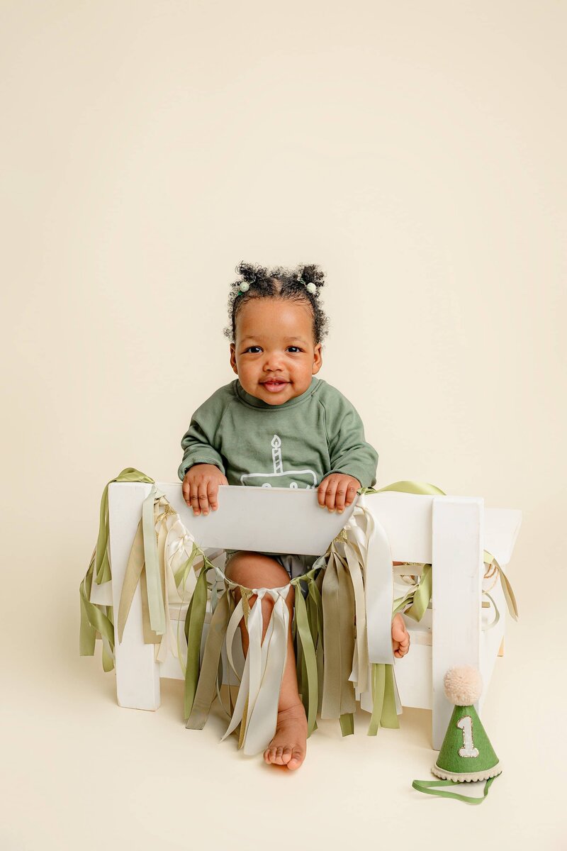 girl sits backward on a white bench as she is dressed in green