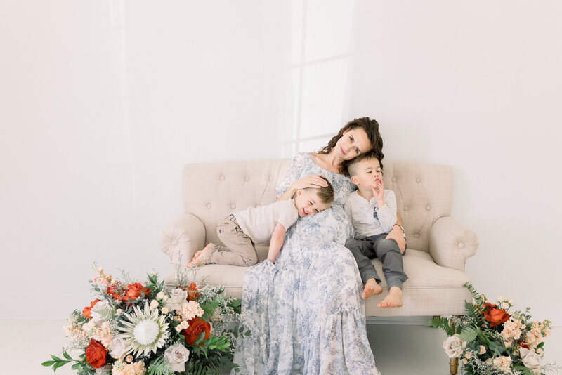 expecting mother sitting on couch with two sons taken by Sacramento Family Photographers kelsey Krall
