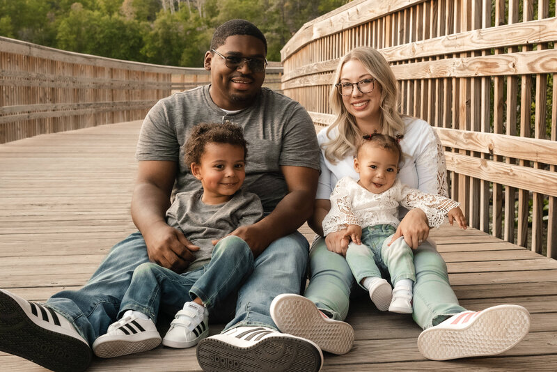 Biracial family smiles at camera with kids on a bridge in Eagan, Minnesota.